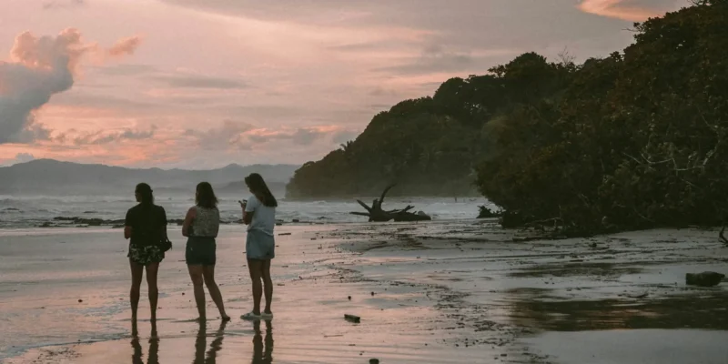 Três pessoas na praia ao pôr do sol na Costa Rica Mergulho com tubarões