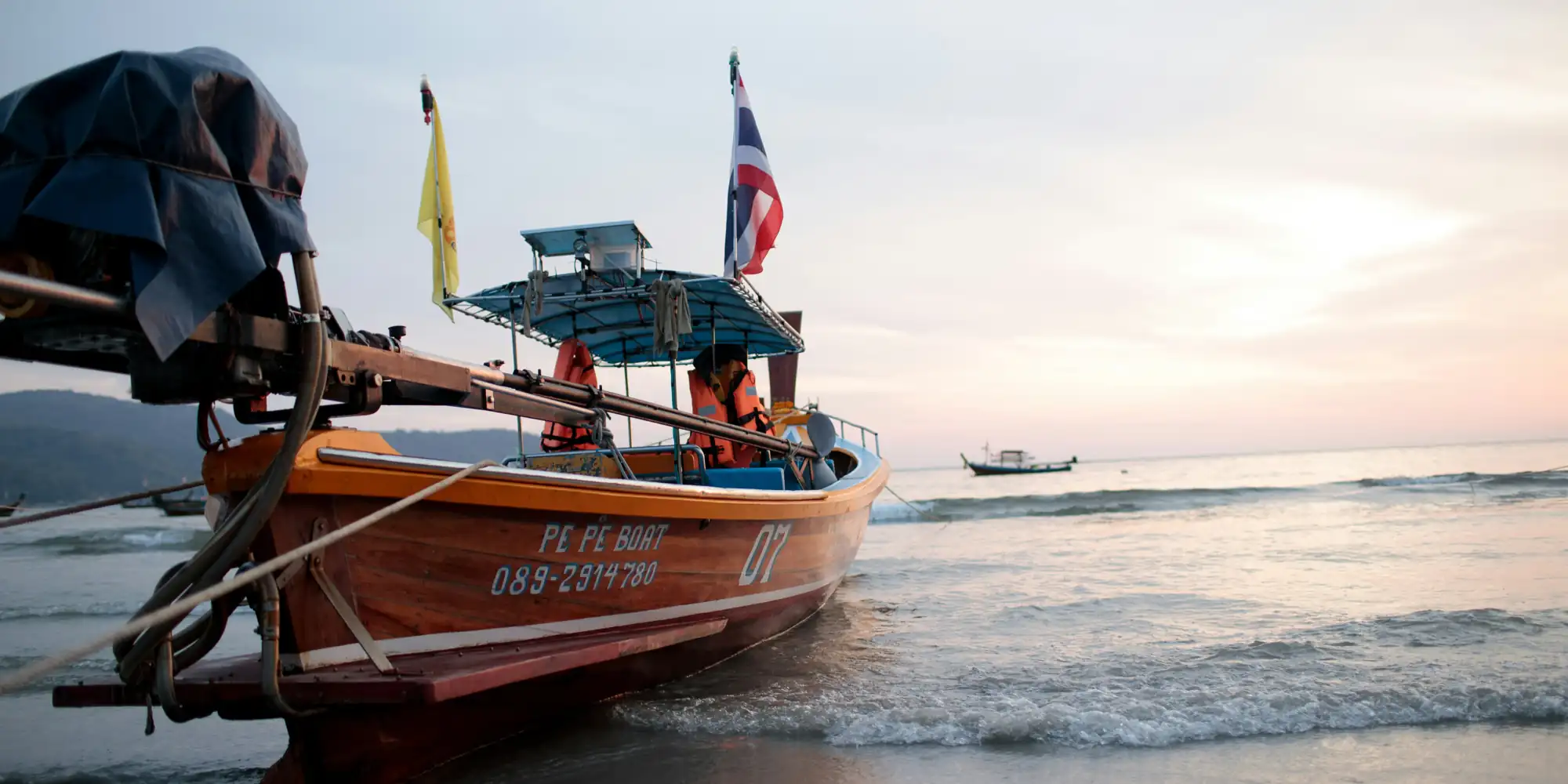 Barco de madeira meio na areia meio na água na Tailândia