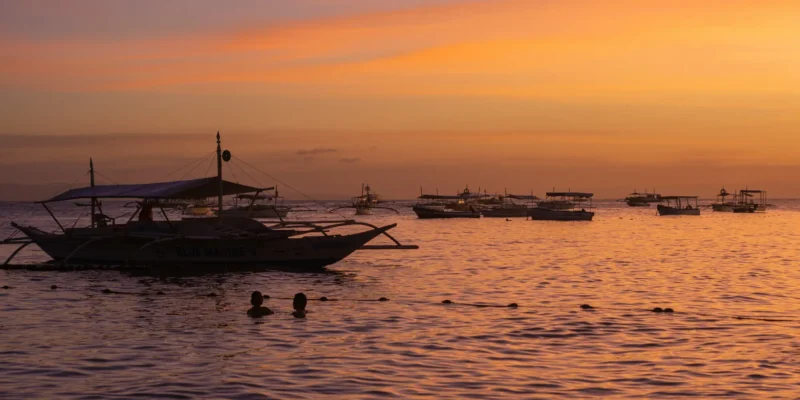 Barcos de pesca no mar ao pôr do sol ao largo de Bohol, Filipinas