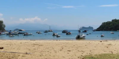 Vista de uma praia de Ilha Grande com barcos e um navio de cruzeiro