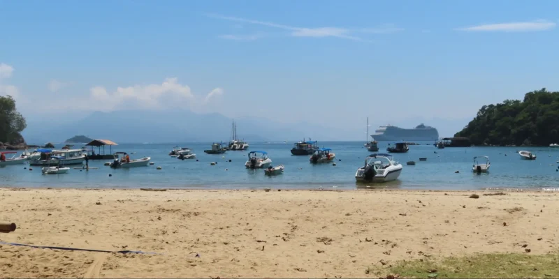Vista de uma praia de Ilha Grande com barcos e um navio de cruzeiro