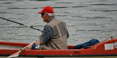 Homem com vara de pesca em um caiaque vermelho na água