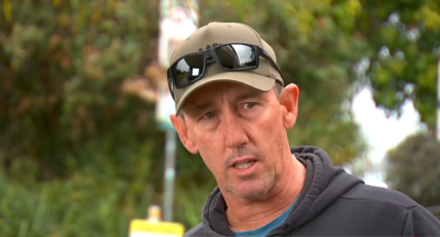 O surfista Matthew Devine de boné com óculos de sol na aba durante uma entrevista