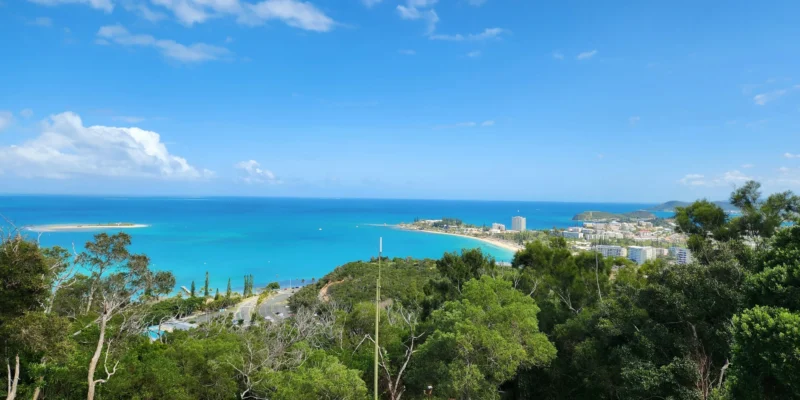 Vista de uma colina arborizada sobre a baía turquesa e a cidade de Nouméa