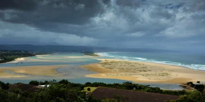 Vista da lagoa, da praia e do oceano em Plettenberg Bay sob nuvens escuras de tempestade
